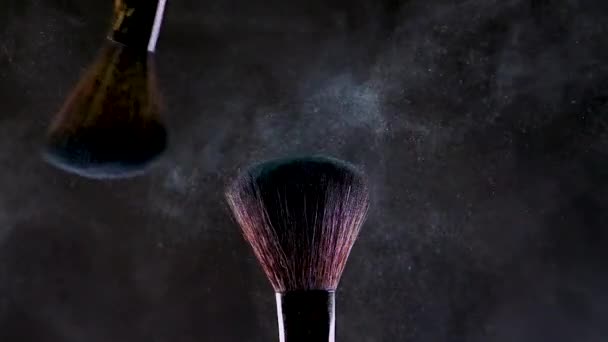 Two makeup brushes with bright eye shadow. Glitter and shadows scatter in the air - Filmagem, Vídeo