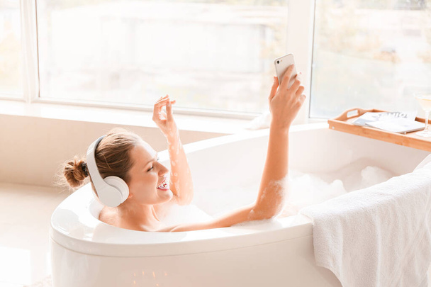 Mulher bonita ouvindo música enquanto toma banho em casa
 - Foto, Imagem