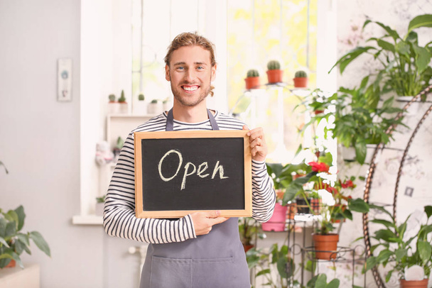Portrait of male florist holding chalkboard with text OPEN in shop - Photo, Image