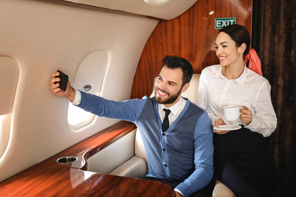 Couple taking selfie on board the modern private airplane - 写真・画像