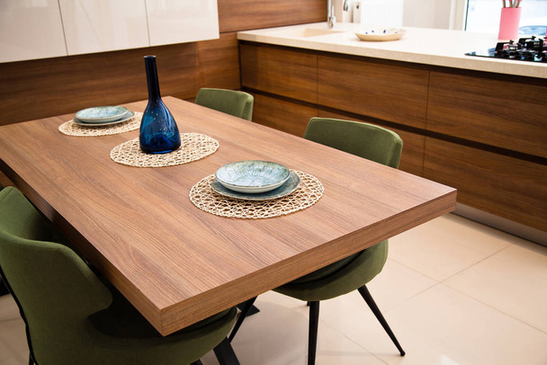 モダンなキッチン、木製のクルミのダイニングテーブルと緑の椅子 - 写真・画像
