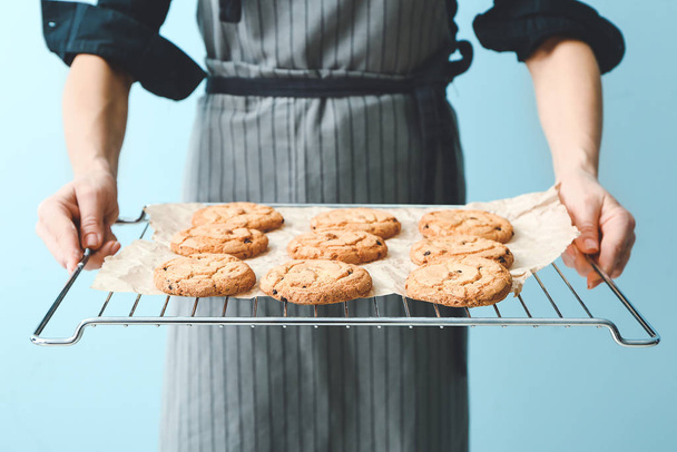 Woman holding cooling rack with tasty cookies on color background - Photo, Image