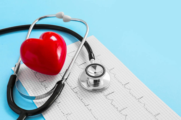 Stethoscope, red heart and cardiogram on color background. Cardiology concept - Photo, Image