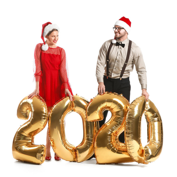 Ευτυχισμένο ζευγάρι σε καπέλα Άγιος Βασίλης και με μπαλόνια αέρα σε λευκό φόντο - Φωτογραφία, εικόνα