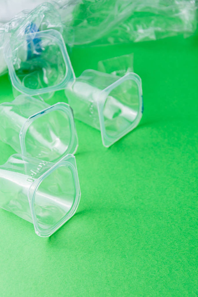 Vista superior de recipientes de plástico sobre fundo verde, para reciclagem, em vertical com espaço de cópia
 - Foto, Imagem