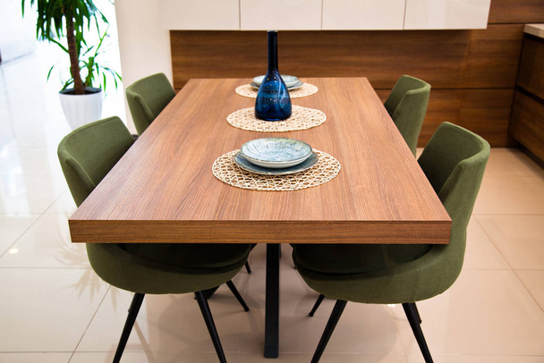 Современная кухня, деревянный ореховый обеденный стол и зеленые стулья
 - Фото, изображение