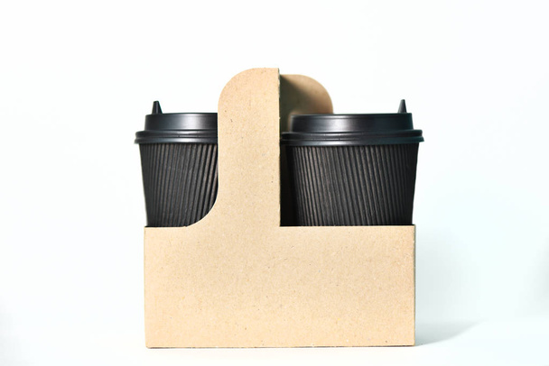 Одноразовые бумажные чашки черного цвета в контейнере Бумажные чашки для горячего кофе. Кофе с собой. Бумажная чашка для кофе
 - Фото, изображение