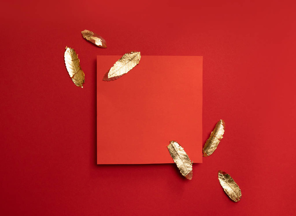 Kreatív kompozíció piros levélkerettel, piros alapon arany levelekkel. - Fotó, kép