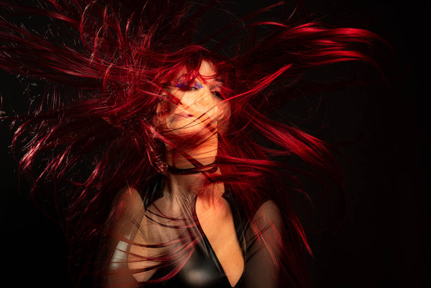 Een meisje op een zwarte achtergrond met dubbele belichting met rood haar  - Foto, afbeelding