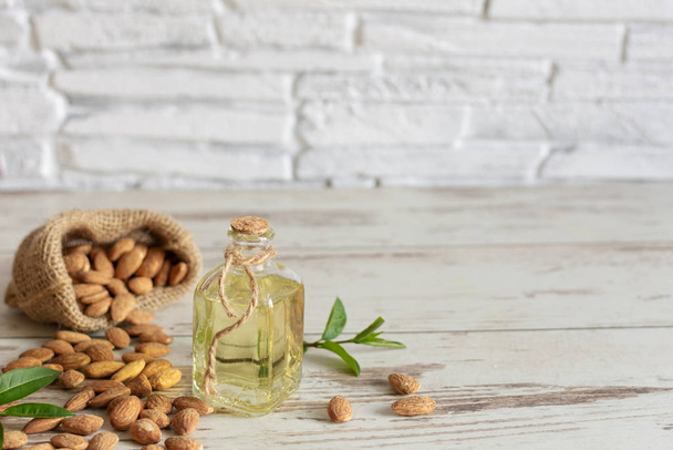 Almond oil in bottle and almond nuts on wooden background. - Fotografie, Obrázek