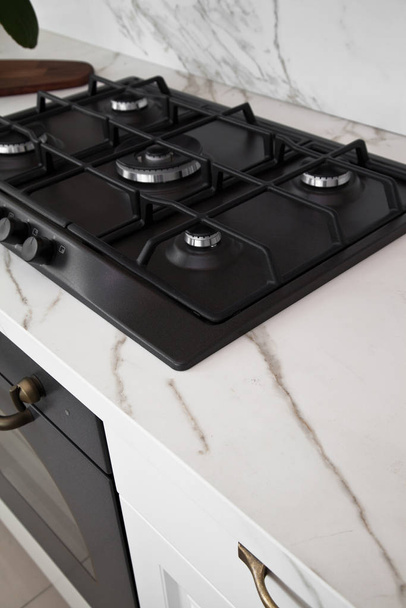 Современная чистая кухня и черная встроенная газовая печь
 - Фото, изображение