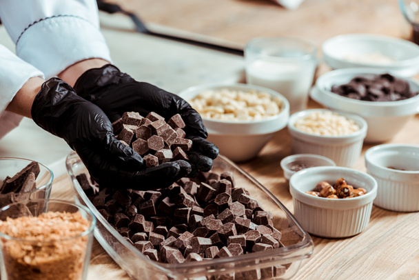 cropped view of woman in black latex gloves holding chocolate cubes  - Fotografie, Obrázek