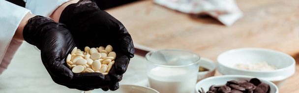 panoramic shot of woman in black latex gloves holding white chocolate chips  - Photo, Image