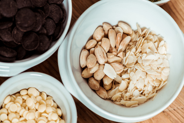 top view of nutritious nuts near chocolate chips in bowls  - Photo, Image
