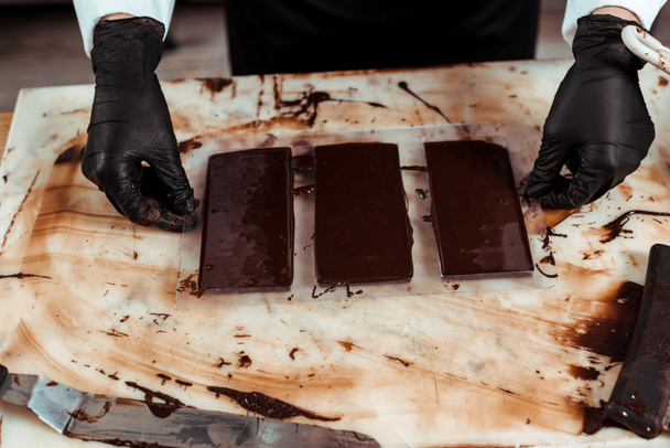 vágott kilátás csokoládé gumikesztyűben közelében csokoládé szeletek  - Fotó, kép