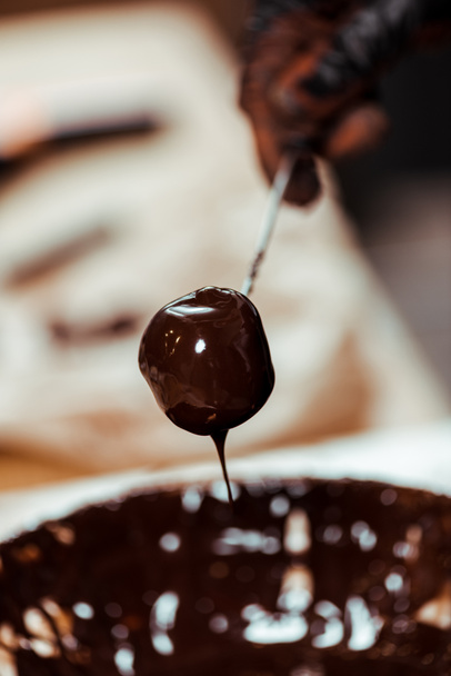 vista recortada de chocolatero sosteniendo palo con sabrosos dulces cerca de chocolate derretido
 - Foto, Imagen