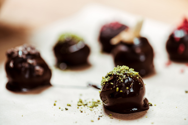 selective focus of sweet chocolate ball with pistachio powder near candies  - Foto, Imagen