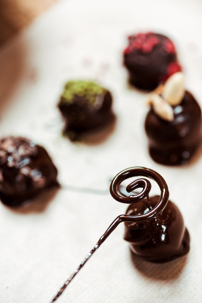 κοντινό πλάνο του στροβιλισμού με λιωμένη σοκολάτα κοντά σε μπάλες σοκολάτας - Φωτογραφία, εικόνα