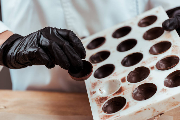 cropped view of chocolatier holding chocolate candy  - Fotoğraf, Görsel