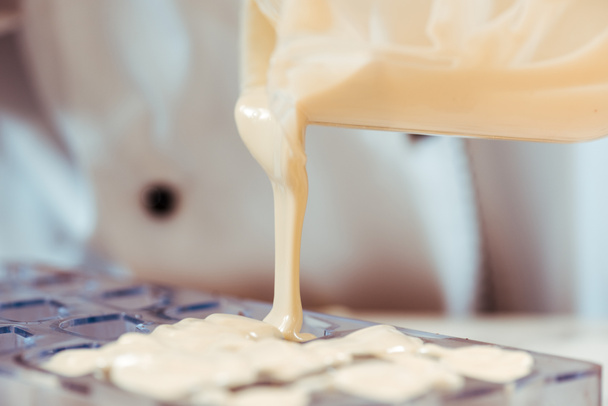 weiße geschmolzene Schokolade aus Krug in Eisfach gießen  - Foto, Bild