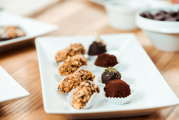 selective focus of chocolate truffles and tasty candies on plate  - Fotó, kép