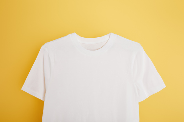 top view of basic white t-shirt on yellow background - Foto, imagen