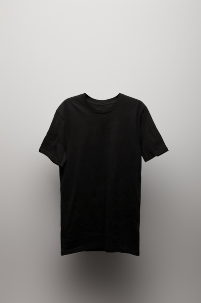 blank basic black t-shirt on grey background - Foto, afbeelding