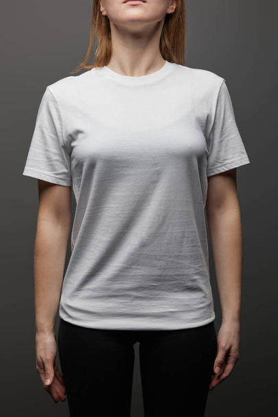 cropped view of woman in blank basic white t-shirt on black background - 写真・画像