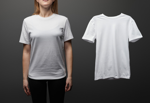 corte vista de mulher perto de branco básico branco t-shirt no fundo preto
 - Foto, Imagem