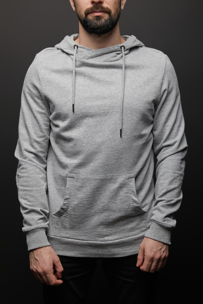 cropped view of bearded man in blank basic grey hoodie isolated on black background - Foto, afbeelding