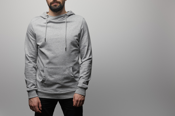 cropped view of bearded man in blank basic grey hoodie isolated on grey - Foto, Imagem