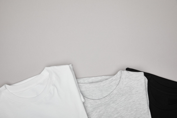 верхний вид пустых основных черных, белых и серых футболок, изолированных на сером
 - Фото, изображение