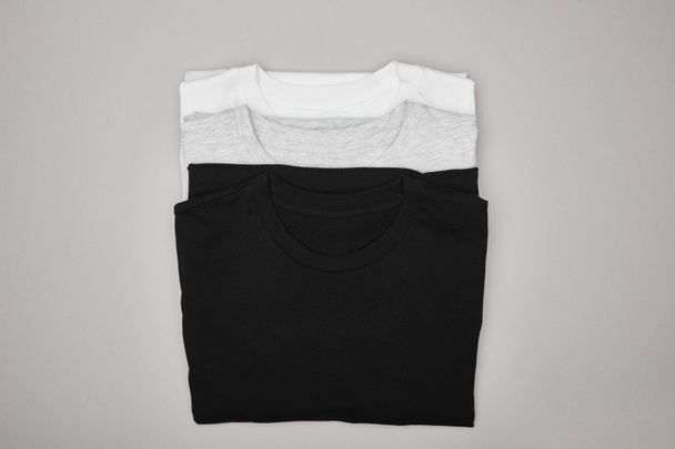top view of blank basic black, white and grey t-shirts isolated on grey - Foto, afbeelding