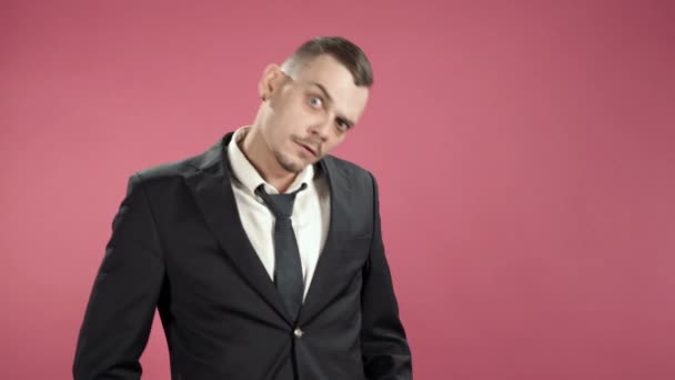 Annoyed young man in suit against pink background - Video
