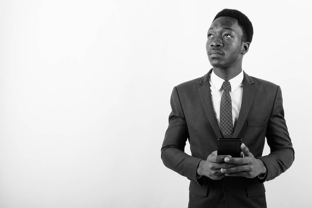 Young handsome African businessman using mobile phone against white background - Photo, image
