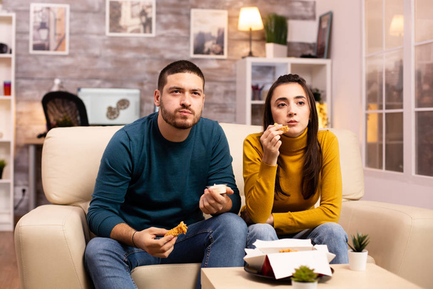 Giovane coppia mangiare pollo fritto davanti alla TV
 - Foto, immagini