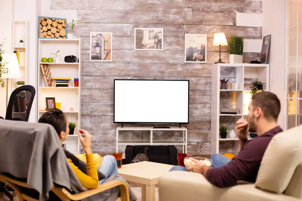 Para patrząc na izolowany ekran TV w przytulnym salonie - Zdjęcie, obraz