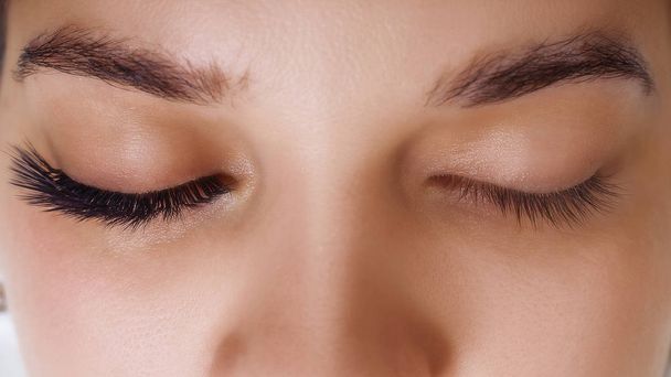 Eyelash Extension Procedure. Woman Eye with Long Blue Eyelashes. Ombre effect. Close up, selective focus. - Foto, imagen