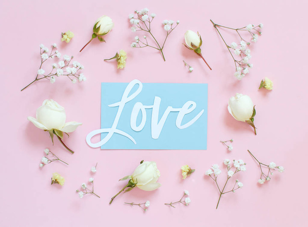 Bloemen en woord Liefde op een lichtroze achtergrond - Foto, afbeelding