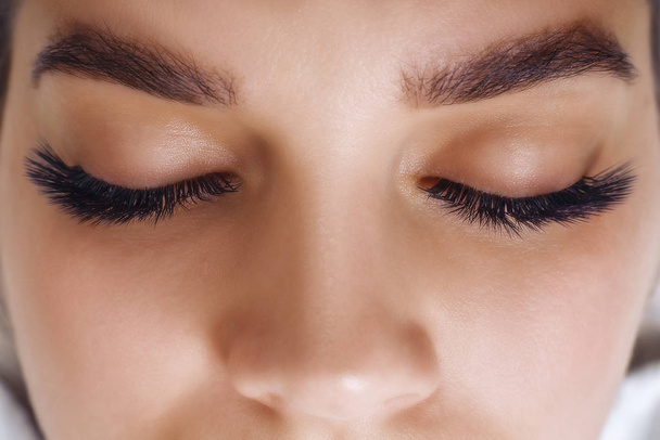 Eyelash Extension Procedure. Woman Eye with Long Blue Eyelashes. Ombre effect. Close up, selective focus. - Foto, immagini