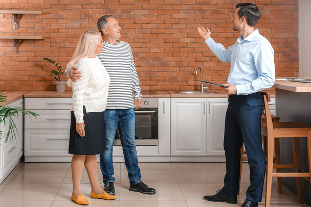 Male real estate agent showing mature couple a new house - Zdjęcie, obraz