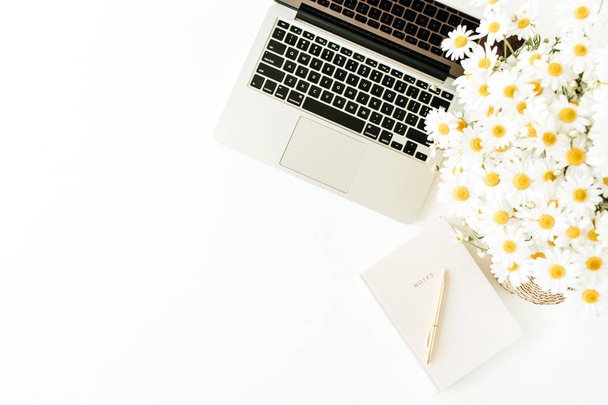 Home office desk workspace with laptop, chamomile bouquet and notebook on white background. Flat lay, top view freelance work hero header. - Photo, Image