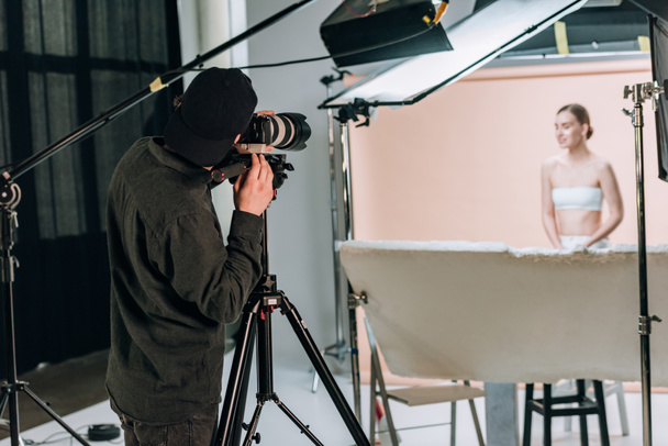 Foco seletivo do videógrafo filmando modelo feminino bonito no estúdio de fotos
 - Foto, Imagem