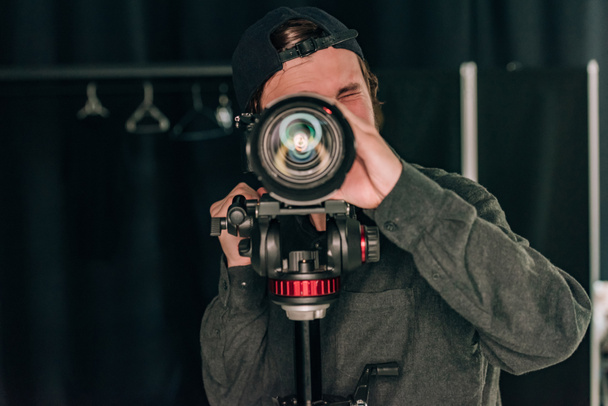 Videografo che guarda attraverso la fotocamera in studio fotografico
 - Foto, immagini