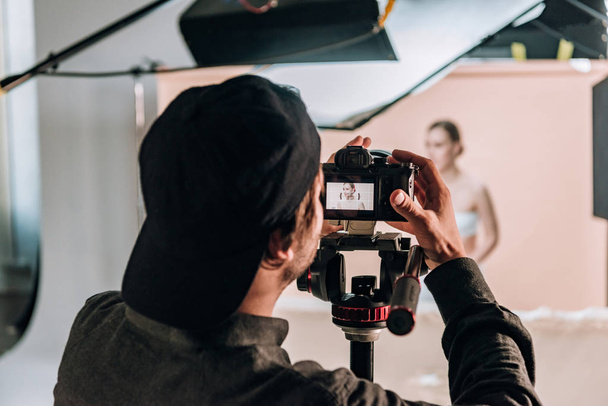 Focus sélectif du vidéaste avec caméra travaillant avec une belle femme en studio photo
 - Photo, image