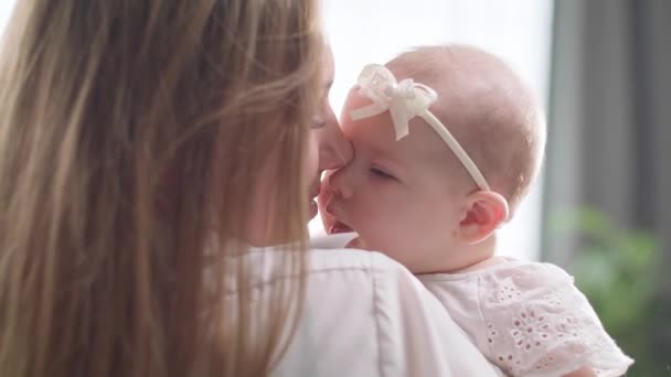 Η μαμά φιλάει και αγκαλιάζει μια μικρή κόρη στον πρωινό ήλιο - Πλάνα, βίντεο