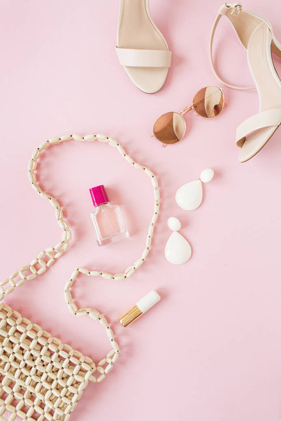 Composición de moda de verano con accesorios femeninos sobre fondo rosa. Bolsa, perfume, gafas de sol, zapatos, pendientes, lápiz labial. Piso tendido, vista superior
. - Foto, imagen
