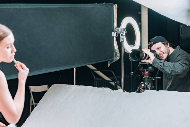 Επιλεκτική εστίαση του videographer γυρίσματα όμορφο μοντέλο με ρολό μασάζ στο στούντιο φωτογραφιών - Φωτογραφία, εικόνα