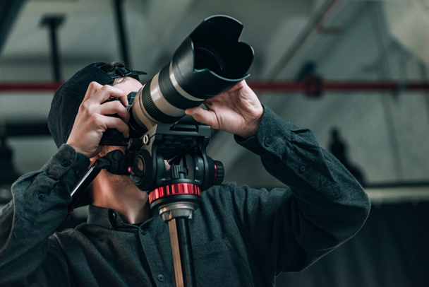 Tiefansicht des Videographen mit Kamera auf Stativ im Fotostudio - Foto, Bild
