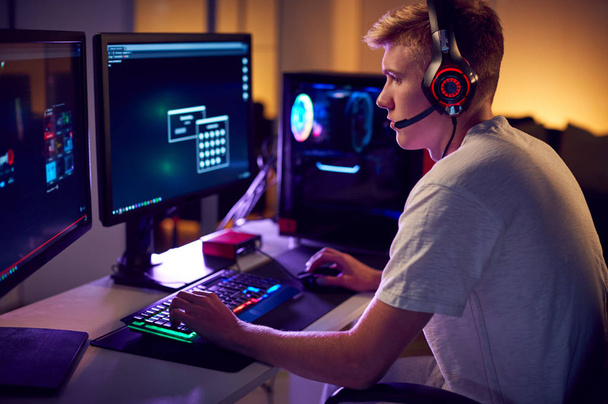 Male Teenage Hacker Sitting In Front Of Computer Screens Bypassing Cyber Security - Foto, Imagem